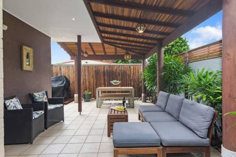 The undercover patio is furnished with a dining bench, outdoor sofa and armchairs, plus a BBQ grill
