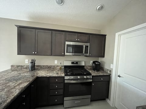 Large kitchen with walk plenty of cabinets, dishwasher, microwave and stove