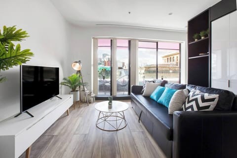 An open-plan space features a living area furnished with a sofa that doubles as a sofa bed, vintage-style armchair, marble-topped coffee table and a wide-screen TV with Netflix.