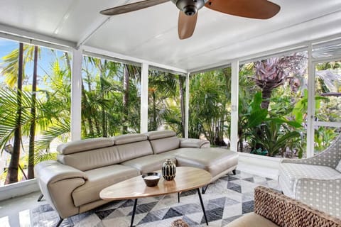 Sunlight streams through the glass walls, illuminating the living room with a warm, inviting glow.