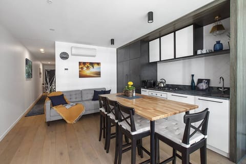 A compact but open floor plan makes use of every nook and cranny, with a high-top table offering extra benchtop space and four stools so the entire group can come together for a meal.