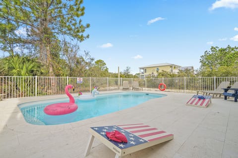 Sunny shared pool area with loungers, cornhole boards, and plenty of deck space to relax. Fully fenced for safety and shared with Unit A—perfect for cooling off after a beach day,
