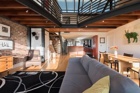 The chic open living area boasts mid-century modern style with soaring ceilings and exposed brick, complemented by a Samsung 55” Smart TV for your entertainment.