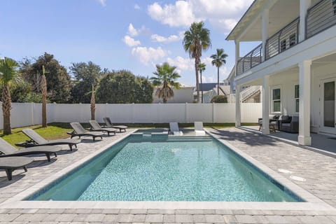 Sunlit pool & patio w/ loungers, framed by palms and a breezy covered deck.