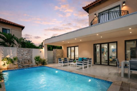 Private backyard by night with pool, dining table and conversation set