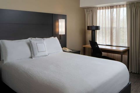 Sink into crisp bedding beside soft daylight and calm views.