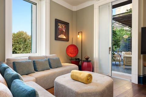 Bright living room with large windows, a cozy sectional sofa, stylish decor, and direct access to the private terrace — the perfect spot to unwind after a day exploring Rome.