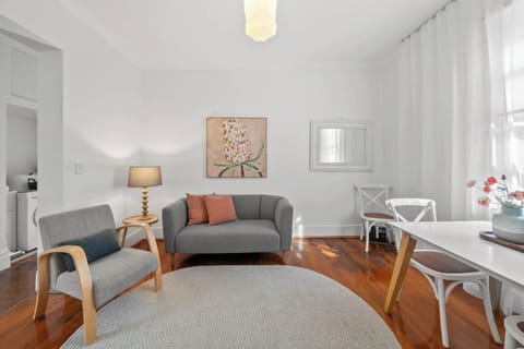 ‎A cosy and minimalist living-dining area featuring a comfy sofa, TV, and relaxing seating — perfect for unwinding after a day out.