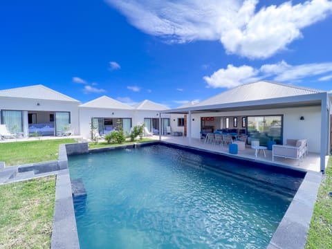 Picture of a peaceful holiday villa featuring a crystal-clear pool, sun loungers, and an open living area overlooking the pool.