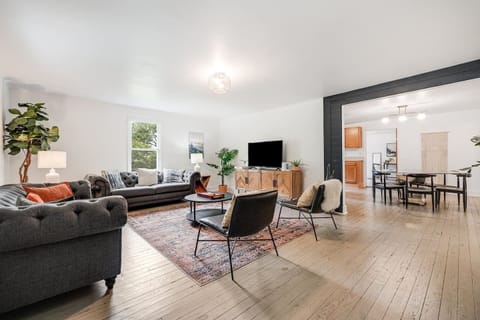 Professionally remodeled living room with two large, comfy couches, two lounge chairs, a coffee table, super fast WiFi, Roku smart TV, and open-living concept leading into kitchen