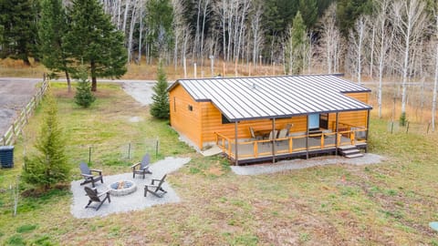 Nestled against a backdrop of tall pines, this cozy cabin features a spacious front deck and a private fire pit—perfect for relaxing after a day of adventure.
