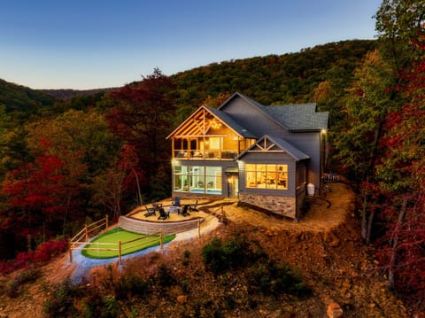 A stunning 5 bedroom luxury Smoky Mountain retreat featuring panoramic views, private putting green, gas firepit, indoor pool, hot tub, outdoor giant chess set, game room, and theater room.
