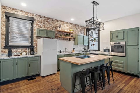 Kitchen: Our kitchen combines modern amenities with rustic charm, featuring a central island for dining and a backdrop of exposed brick.
