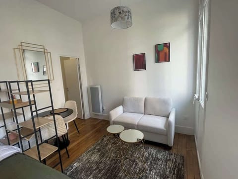 Séjour avec canapé blanc, étagère, table ronde et parquet — espace de vie lumineux du studio Le Chill Toulouse