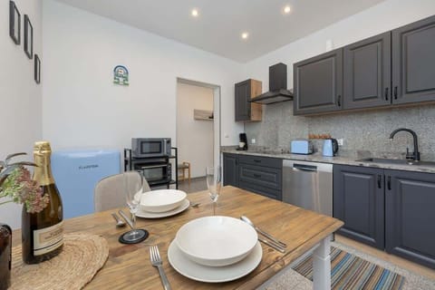 A different angle of the kitchen and dining area, emphasizing the stylish mix of wood and dark finishes, along with a neatly arranged dining setup.