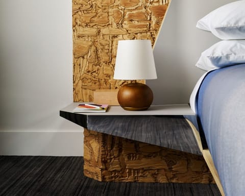Sink into plush bedding beside warm, artisan wood textures.