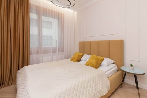 A bedroom with a large wooden headboard, crisp white bedding, and mustard-yellow accent pillows, creating a bright and inviting sleeping area.

