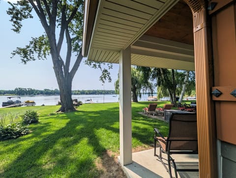 Covered patio outside of the primary bedroom overlooking the lake and yard
