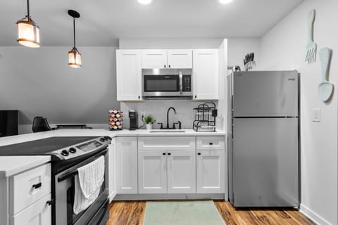 Your fully equipped kitchen awaits with stainless steel appliances, white cabinetry, and warm pendant lighting for memorable meal preparations.