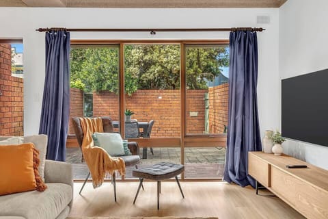 The dining and living area features a wall-hung TV, and opens into the sunny patio
