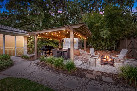 Firepit & Pergola – Private St. Simons Outdoor Oasis - The fenced backyard of this St. Simons Island vacation rental features a string-lit pergola, firepit, and Adirondack chairs—perfect for evening cocktails, marshmallows, or a little moonlight magic.
