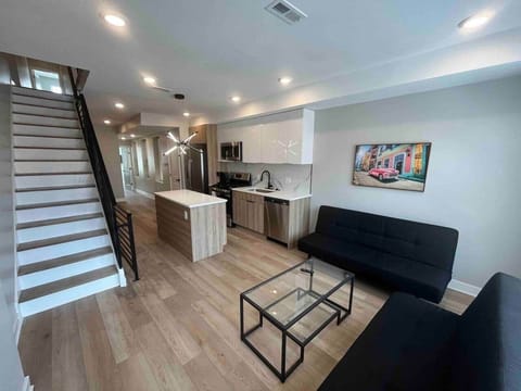 Relax in the inviting living room, equipped with two comfortable sofa beds, a flatscreen TV, and large windows that fill the space with beautiful natural sunlight. The room seamlessly connects to a modern kitchen featuring a convenient breakfast bar.