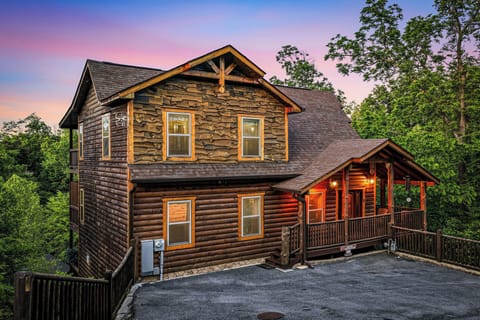 A rustic log cabin nestled among towering trees captures the perfect mountain retreat under a stunning twilight sky.