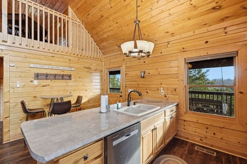Embrace rustic charm in this stunning log cabin kitchen with soaring ceilings and forest views from your dining spot.