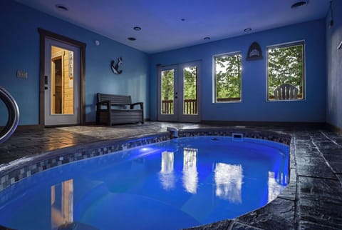 Dive into your private indoor pool sanctuary, where blue waters reflect the serene atmosphere and large windows frame peaceful garden views.