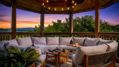 Cozy covered patio showcases mountain vistas at sunset, with plush seating inviting guests to unwind beneath warm ambient lighting and enjoy sweeping natural landscapes.