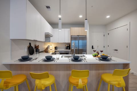 Fully equipped modern kitchen stocked with all culinary essentials and featuring stainless steel appliances with island bar seating.