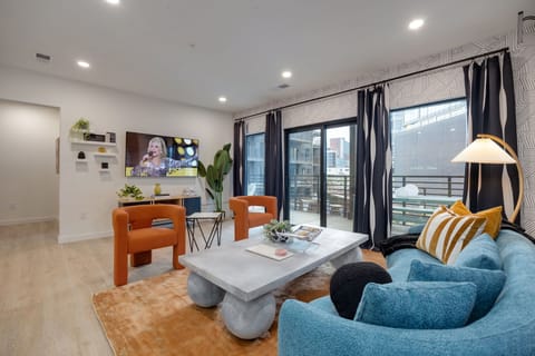 Bright open living space featuring SMART flat-screen TV, designer furnishings, and patio entrance with pool view.