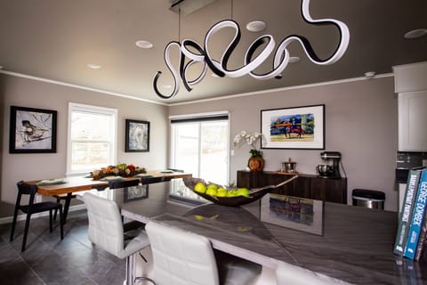 Spacious bar with four stools & modern lighting, facilitating easy socializing with guests in the living room or kitchen.