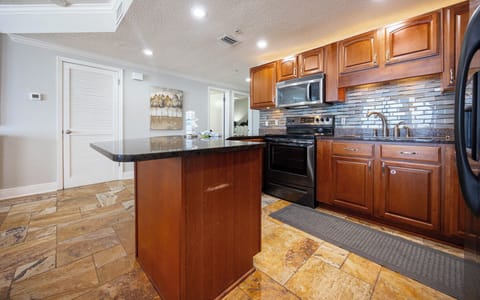Prepare meals in the inviting kitchen featuring rich wood cabinetry, sleek granite counters, and stainless appliances