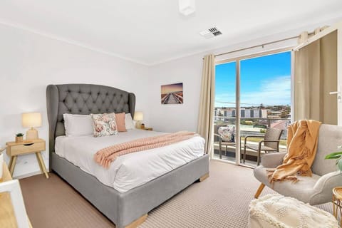 The primary bedroom features a queen-size bed, built-in robes and a private balcony overlooking the sea.