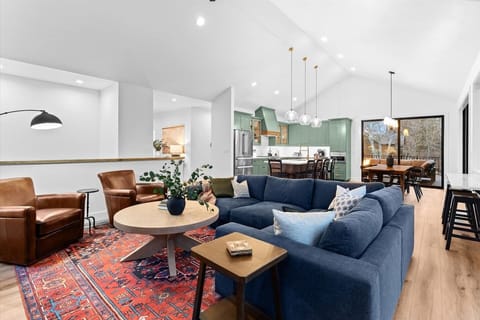 Connected seamlessly to the living room is the open kitchen, where the heart of the home comes to life. A spacious island, adorned with pendant lights, serves as a central gathering spot.