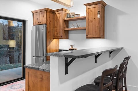 The bar area is equipped with bar stools, creating a casual setting for enjoying drinks or snacks.  Glass doors lead to a walkout, revealing a stunning view of the Flathead River.