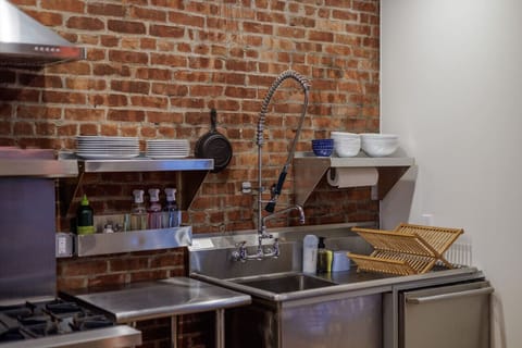 A well-equipped kitchen with stainless steel finishes, open shelving, and a deep industrial-style sink—perfect for cooking like a pro.