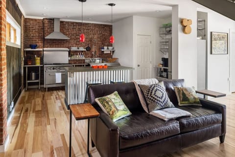 Relax in the open-concept living room, featuring a comfy couch, exposed brick, and a warm, inviting atmosphere.