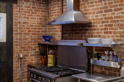 Cook in style with this professional-grade stove, surrounded by exposed brick and open shelving for a true industrial-chic vibe.