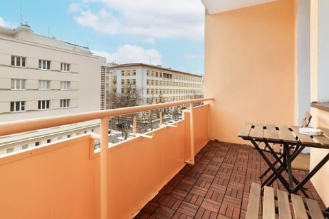 Balcony with outdoor seating and a table, offering a view over the nearby city buildings.