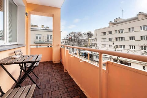 Balcony with outdoor seating and a table, offering a view over the nearby city buildings.