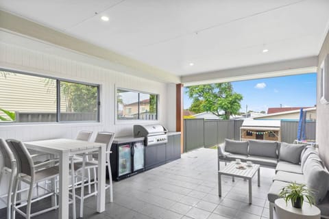 The undercover patio is thoughtfully furnished for relaxation and entertaining, with a corner sofa and table setting providing an inviting spot to dine alfresco and kick back with a glass of wine in the evening. 