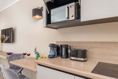 A compact kitchen area with a microwave, kettle, and practical storage solutions.

