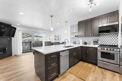 Full kitchen with stainless steel appliances, and breakfast bar.