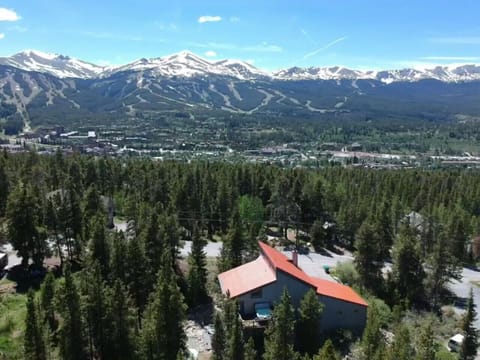 Drone view of back of the home with hot tub and the mountains.