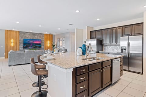 - Modern kitchen with granite countertops stainless appliances and island bar
- Spacious open design connects to living area for family vacation gatherings
- Orlando rental kitchen perfect for groups preparing meals near Disney parks