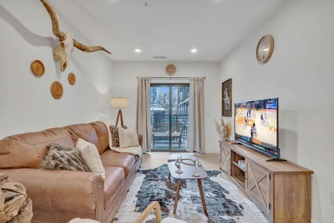 Warm and inviting living space featuring a flat-screen smart TV and designer furnishings with access to the private balcony.