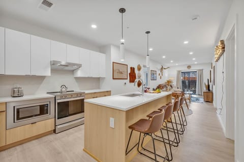 Fully equipped modern kitchen stocked with all culinary essentials and featuring brand new stainless steel appliances with an island offering bar seating.
