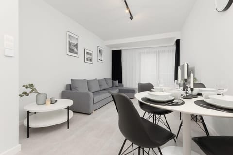 A modern living room with a gray sofa, black dining chairs, and elegant black-and-white decor.